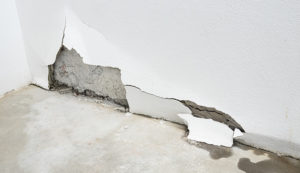 woman looking at damage after a water pipe leak at home | can water leak through wall