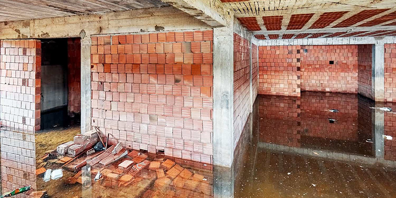 basement of a building under construction filled with dirty flood water | water damage behind brick
